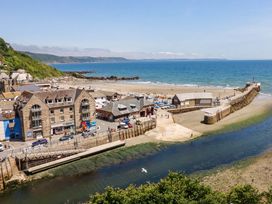 A beach with buildings and a pier at Harbour House in Looe