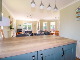 An open-plan living room and dining area with a wooden countertop and blue cabinets at Lodge 9- Lamorna in Tregolds near St Merryn