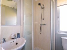 A bathroom with a shower enclosure a sink with taps and a mirror above the sink at Lodge 9- Lamorna Tregolds near St Merryn