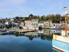 A harbor with boats docked near stone buildings and trees in the background at Lodge 9- Lamorna in Tregolds near St Merryn