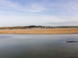 A view of a river with sandy banks and a village with houses and trees in the background at Lodge 9- Lamorna in Tregolds near St Merryn