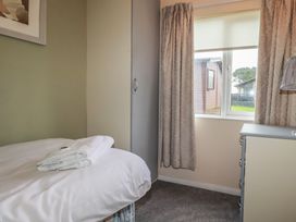 A bedroom with a bed and window at Lodge 9 - Lamorna Tregolds near St Merryn