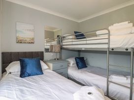 A bedroom with a bunk bed and a single bed at Lodge 9 - Lamorna Tregolds near St Merryn