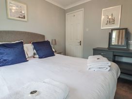 A bedroom with a bed, lamp, and mirror at Lodge 9 - Lamorna Tregolds near St Merryn
