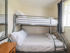 A bedroom with a metal bunk bed next to a window and a wooden drawer at Lodge 18 in St Merryn
