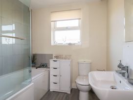 A bathroom with a bathtub and glass shower screen a white cabinet toilet and sink at Lodge 18 in St Merryn