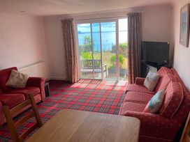 A living room with a sofa, dining table, and television at 1 Penrose Court in Penzance