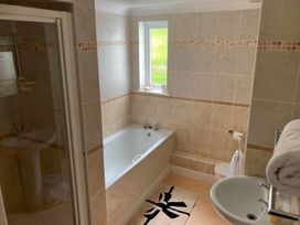 A bathroom with a bathtub, shower, sink, and toilet at 1 Penrose Court in Penzance