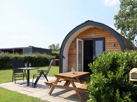 A wooden cabin with outdoor seating at Honeypot Hideaways - Acacia