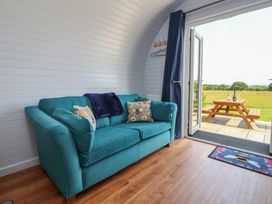 A living room with a sofa and door leading to the outdoors at Honeypot Hideaways - Acacia