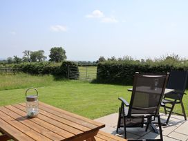 A seating area with a table and chairs in a garden at Honeypot Hideaways - Acacia