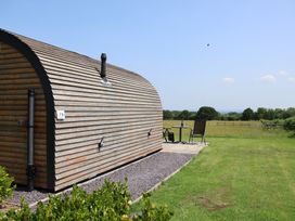 A wooden cabin with outdoor seating at Honeypot Hideaways - Acacia