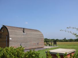 A wooden cabin with a table and chairs outside at Honeypot Hideaways - Acacia