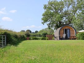 A wooden structure in a grassy area at Honeypot Hideaways - Acacia