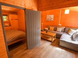 A living room with a door, sofa, and table at Stumps Cross Lodge in Upper Coscombe near Winchcombe