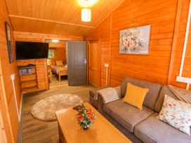 A living room with a sofa and television at Stumps Cross Lodge Upper Coscombe near Winchcombe