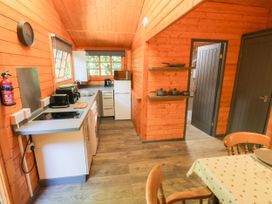 A kitchen with appliances and a breakfast table at Stumps Cross Lodge Upper Coscombe near Winchcombe