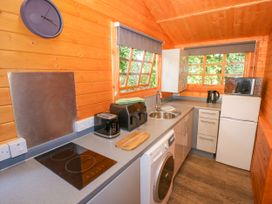 A kitchen with appliances and wooden walls at Stumps Cross Lodge Upper Coscombe near Winchcombe