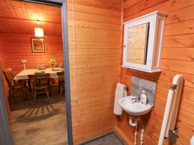 A sink with a mirror in a wooden interior with a dining table at Stumps Cross Lodge Upper Coscombe near Winchcombe