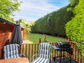 A garden with chairs, table, grill, and a patio umbrella at Stumps Cross Lodge, Upper Coscombe near Winchcombe