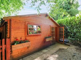A wooden cabin with a gravel path and planters at Stumps Cross Lodge Upper Coscombe near Winchcombe