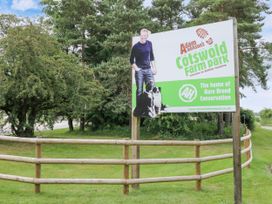 A sign for Cotswold Farm Park in a grassy area with trees at the background near Winchcombe
