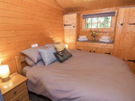 A bedroom with a bed and shelves at Stumps Cross Lodge Upper Coscombe near Winchcombe