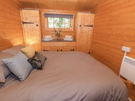 A bedroom with a bed and wooden cabinets at Stumps Cross Lodge Upper Coscombe near Winchcombe