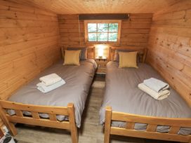 A bedroom with two beds and a window at Stumps Cross Lodge Upper Coscombe near Winchcombe