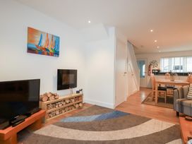 A living room with television, sofa, and dining table at Fistral Palms 2