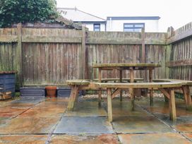 A garden with a wooden table and benches at Fistral Palms 2