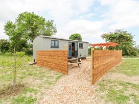 A small shed like building with wooden fencing and a picnic table outside at Woodpecker in Lode near Bottisham