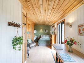 A small room with a bed, chairs, dining table, and wooden ceiling at Woodpecker in Lode near Bottisham