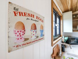 A kitchen wall with a vintage sign about fresh eggs next to a window and a countertop with a faucet and cutting board at Woodpecker Lode near Bottisham