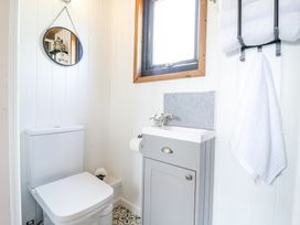 A small bathroom with a toilet a sink with a cabinet a window and towels hanging on a rack at Woodpecker in Lode near Bottisham