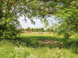 A grassy field with picnic tables and trees framing the view at Woodpecker in Lode near Bottisham