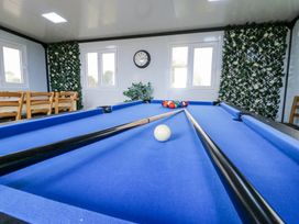 A room with a blue pool table with balls and cues near windows and wooden chairs at Woodpecker in Lode near Bottisham