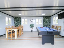 A game room with a pool table and dining table with chairs and a wall mounted TV at Woodpecker in Lode near Bottisham