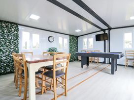 A game room with a pool table wooden chairs and table wall clock and a mounted television at Woodpecker in Lode near Bottisham
