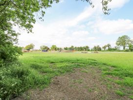 A grassy open field with trees at the edges and some picnic tables in the distance at Woodpecker in Lode near Bottisham