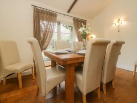 A dining room with a wooden table set with plates and glasses and beige chairs at Meadow Thatch in Cockington