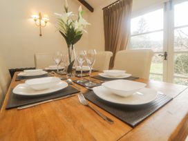 A dining table set with white plates bowls wine glasses and silverware with flowers in a vase at Meadow Thatch in Cockington