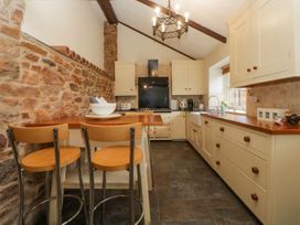 A kitchen with wooden stools stone wall cream cabinets and kitchen appliances at Meadow Thatch in Cockington