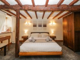 A bedroom with a bed rolled towels wooden beams bedside tables lamps and a wardrobe at Meadow Thatch in Cockington