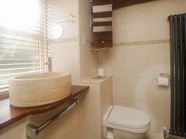 A bathroom with a stone sink on a wooden countertop and a toilet at Meadow Thatch in Cockington