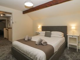 A bedroom with a double bed bedside tables with lamps and rolled towels on the bed at Meadow Thatch in Cockington
