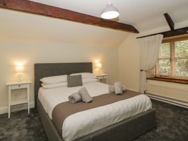 A bedroom with a double bed two bedside tables with lamps a window with blinds and curtains at Meadow Thatch in Cockington