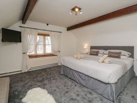 A bedroom with a large bed two pillows with dream text a window with curtains and a mounted television at Meadow Thatch in Cockington