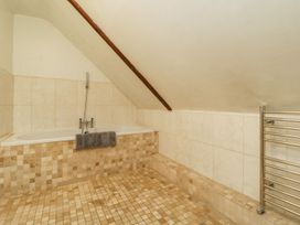 A bathroom with a bathtub under a slanted ceiling and a heated towel rail at Meadow Thatch in Cockington