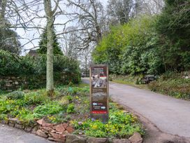 An entrance path with a welcome sign and flowerbed at Cockington Country Park in Cockington